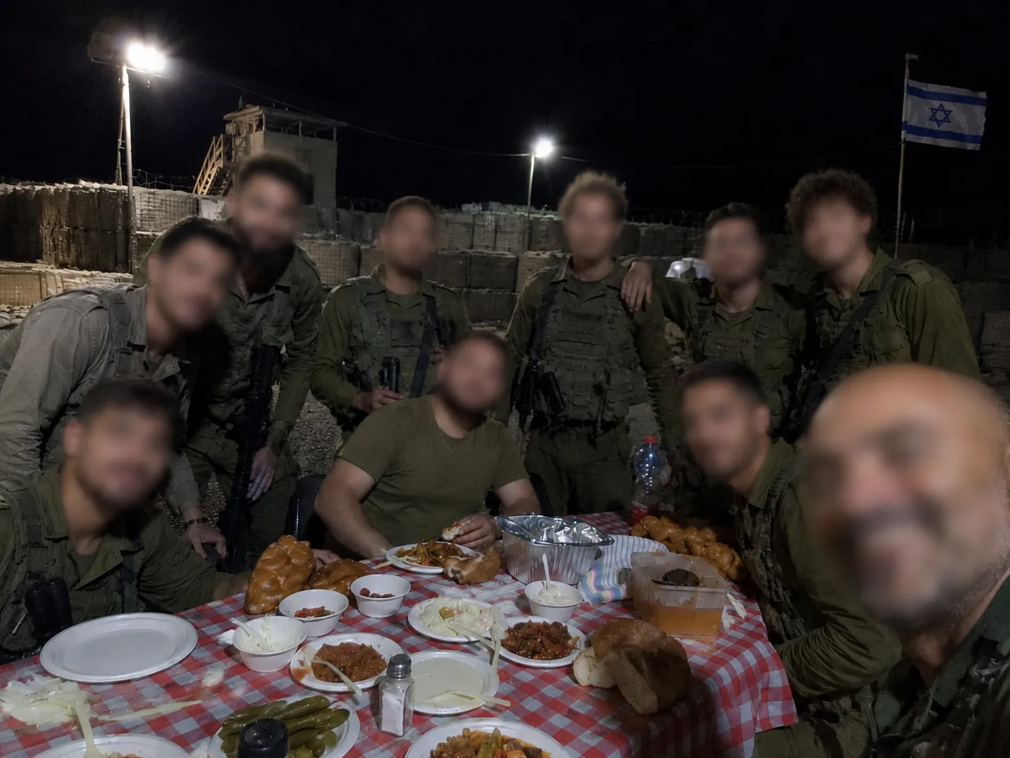 Soldiers and volunteers sharing a candlelit meal under hanging lights